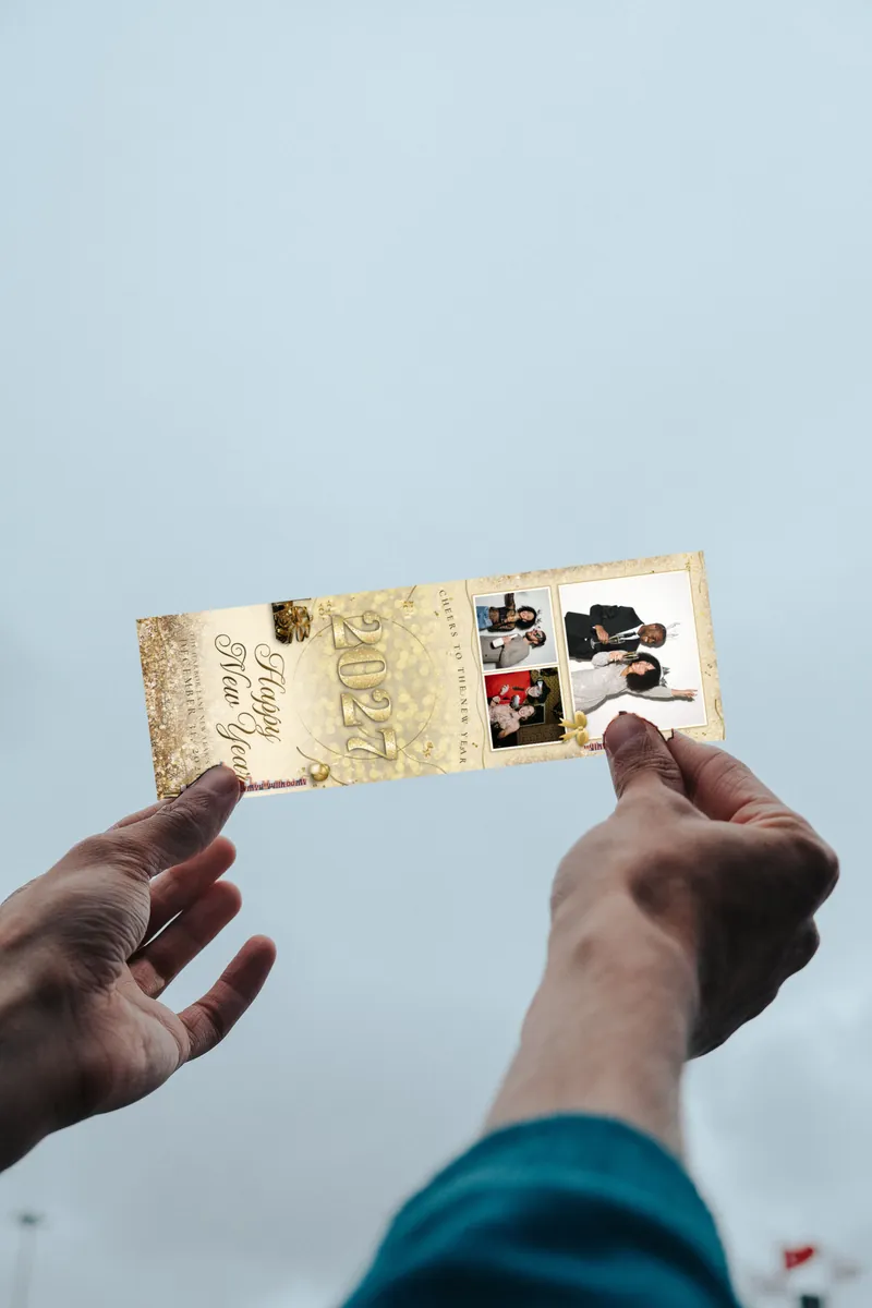 A Champagne Toast New Year's Eve 2027 photo strip held up to the sky in two hands